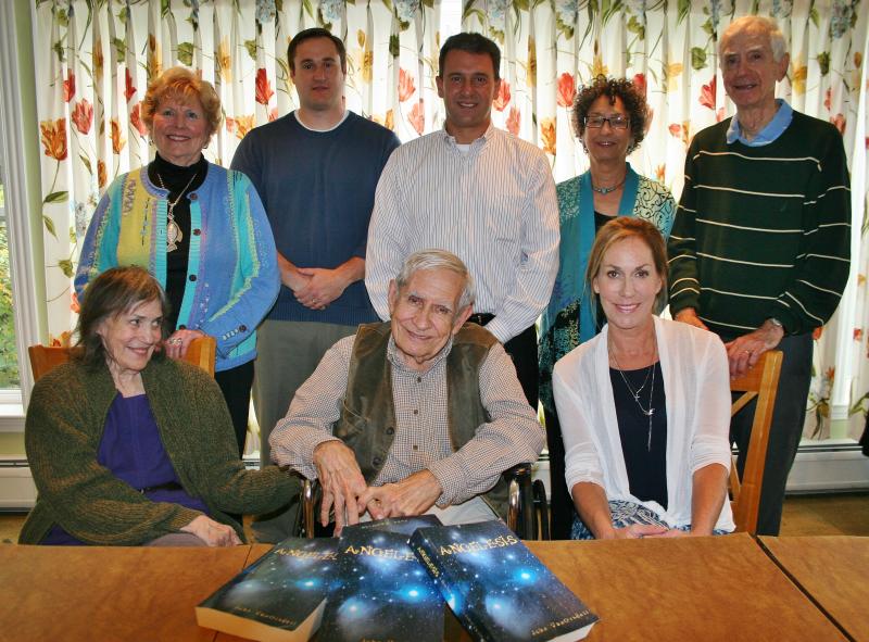 With four copies of his novel, “Angelesis,” resting in front of him, John VanOrsdell of Boothbay is joined at the unveiling by his wife, Alys, left, their daughter, Lisa Amundson, right, and in back, from left, Estelle Appel, Jim Chaousis, Emilio Coppola, Jill Tupper and Ed Kuljian. KEVIN BURNHAM/Boothbay Register