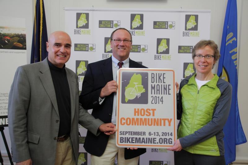 Boothbay Harbor Town Manager Tom Woodin, center, accepts a BikeMaine street sign from BikeMaine board member Mark Ishkanian and Ride Director Kim True in Portland on February 4. Boothbay Harbor is one of six Maine communities that bicyclists will visit next September. Boothbay Harbor is the only community where cyclists will stay for two nights. Courtesy of BikeMaine Photo of Tom Woodin