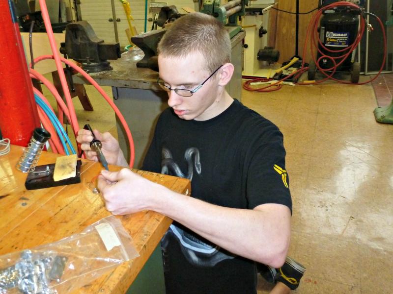 Senior Austin Crocker carefully soldering tips of wires that will go inside his guitar. KATRINA CLARK/Boothbay Register