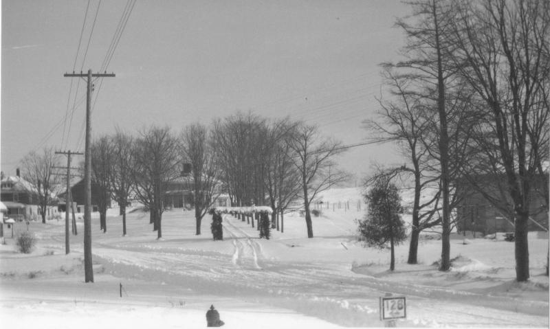 This 1930 winter shot looks east at Boothbay Center. The Spinney-McDougall-Boothbay Green house and barn is to the left. It was built in 1912 on the cellar of an earlier Spinney house. The 1797 Kenniston house is a little left of center. The entrance seems to be decorated for Christmas, and the trees appear to have been carefully planted, perhaps nine years earlier when the house was the clubhouse for the new golf course. On the right, the Horace Giles house is under construction, a Sears kit home, I believe. The Arthur Dodge blacksmith shop was moved back to allow room for the house; Horace placed his new house back from the road to preserve the Teels' view from the Kenniston house. If anyone knows when Route 128 became Route 27, Jolly Arsenault and I would like to know! Late 1930s with all the WPA-inspired road building projects? Courtesy of Evelyn Blake