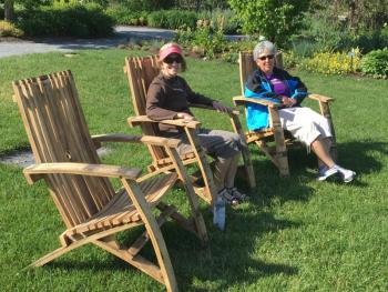 The new chairs built from barrels by Boothbay Region High School students for Coastal Maine Botanical Gardens get tested by a couple of women on a recent day. Courtesy of Kris Folsom/CMBG