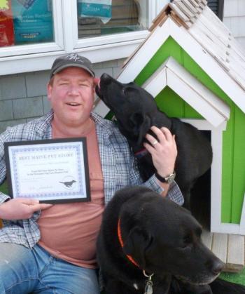 Owner Don Kingsbury holds Two Salty Dog’s award, as Max the lab decides this “photo opportunity” would be better served as a puppy-kiss opportunity. Coal the lab relaxes in front.  KATRINA CLARK/Boothbay Register