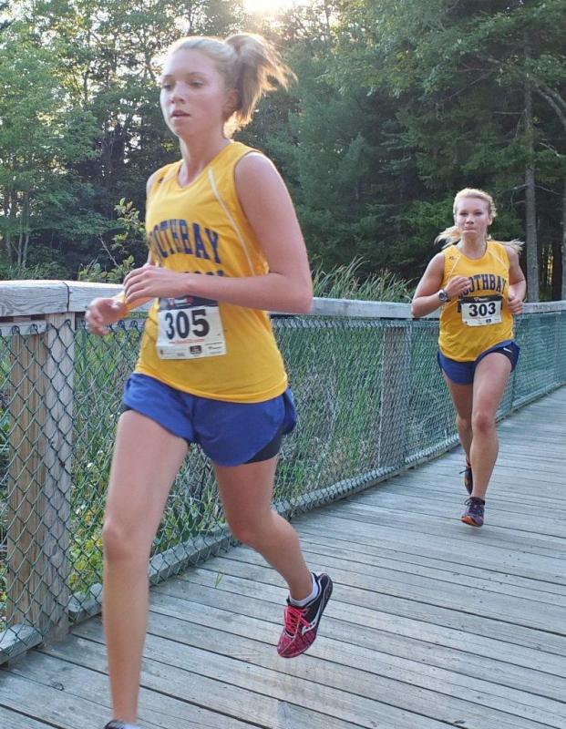 Hannah Morley and Morgan Crocker cross the bridge at Penny Lake. Morley and Crocker finished second and fifth place respectively at the first home meet of the season. Below, Brady Duncan and David Machon sprint toward the finish line. The boys team earned third place out of five MVC teams at the September 12 meet hosted by Boothbay Region High School. RYAN LEIGHTON/Boothbay Register Hannah Morley and Morgan Crocker cross the bridge at Penny Lake. Morley and Crocker finished second and fifth place respectively at the first home meet of the season. RYAN LEIGHTON/Boothbay Register