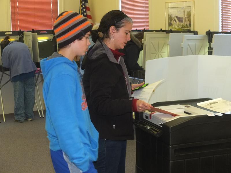 Sarah Goodroe inserts the ballot into the machine as her son Eli watches at the Boothbay Town Office, November 6. RYAN LEIGHTON/Boothbay Register Sarah Goodroe inserts the ballot into the machine as her son Eli watches at the Boothbay Town Office, November 6.