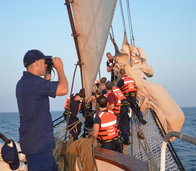 On the Eagle bowsprit, a crew furls the jibs while the southwestern horizon is scanned. (Photo by Lynda Clancy)
