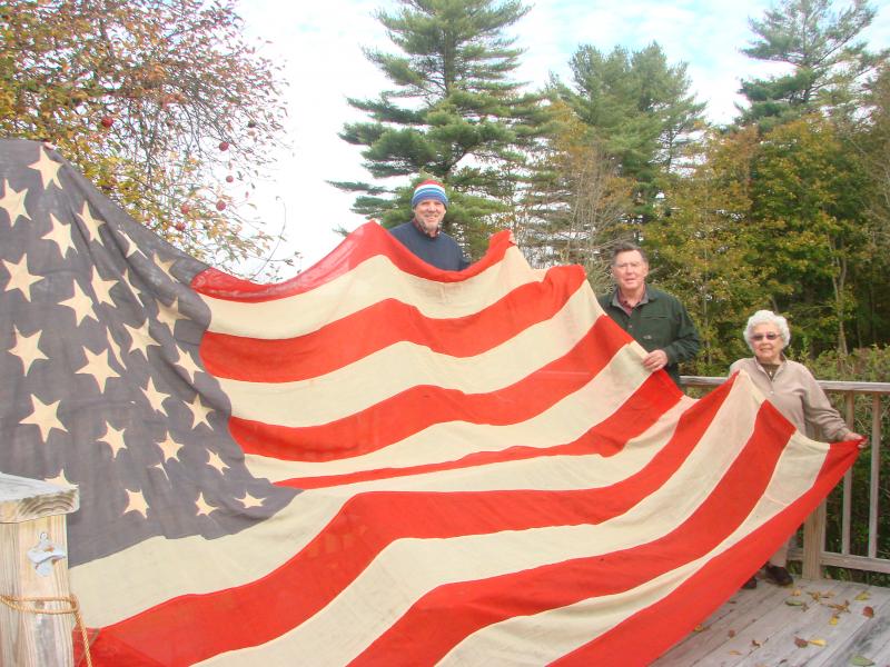 Wiscasset author Phil DiVece, left, Lincoln County Historical Association President Ed Kavanagh and longtime Wiscasset resident Bee King, now of East Boothbay, hold up an 1896 flag King’s grandmother sewed. King donated it to the historical association on October 28. SUSAN JOHNS/Wiscasset Newspaper Wiscasset author Phil DiVece, left, Lincoln County Historical Association President Ed Kavanagh and longtime Wiscasset resident Bee King, now of East Boothbay, hold up an 1896 flag King’s grandmother sewed. King donated it to the historical association on October 28. SUSAN JOHNS/Wiscasset Newspaper