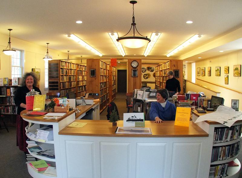 LINDA BREWER, left, Helen Meserve and Jane Lunt work the new front desk, built by Mike Elkins. SUZI THAYER/Boothbay Register