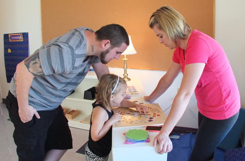 ALEX GOREY AND JACKIE MARKEE help their daughter Mia, 3, with a puzzle at the new Harbor Montessori School in Boothbay Harbor. SUZI THAYER/Boothbay Register