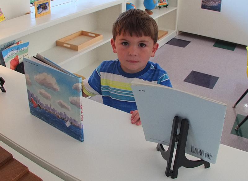 BYRAN HILLS looks over some of the books the new Montessori school has to offer. SUZI THAYER/Boothbay Register
