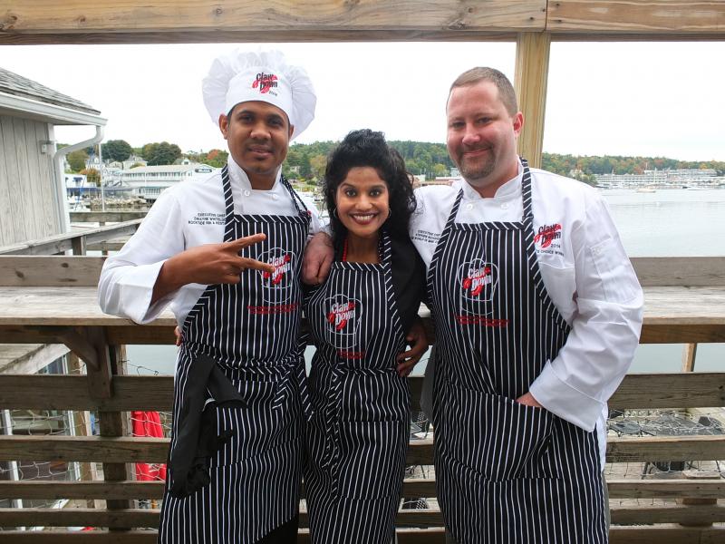 Chefs Dwayne Whitelocke and Steve Richards on the deck of Mine Oyster with their cheerleader and biggest fan, Boothbay Harbor Region Chamber of Commerce’s Cherie Scott. SUZI THAYER/Boothbay Register