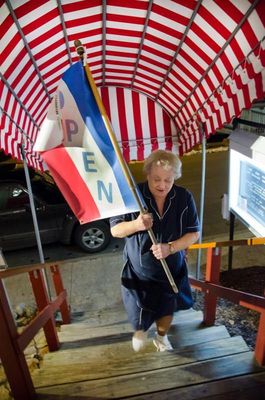 Waitress Cheryl Rice brings in the "Open" flag for the last time as the Ebb Tide restaurant closes Thursday night after exactly 40 years of operation. Courtesy of Peter Southwick