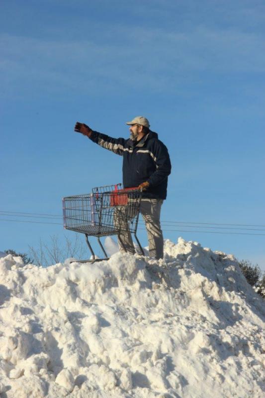 Tom Dewey climbs up “Mount Meadow Mall” (the giant snowbank in shopping center’s parking lot) to retrieve a cart someone had placed on top. But he couldn’t resist playing once he got up there. Here he pretends to grab a can off a shelf while shopping. Courtesy of Leisha J. MacDougall.