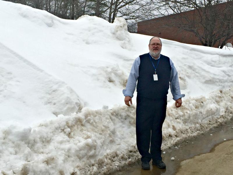 Boothbay Region Elementary School Principal Mark Tess stands outside where the entrance to the playground should be, where a snowbank taller than he is stands instead. KATRINA CLARK/Boothbay Register