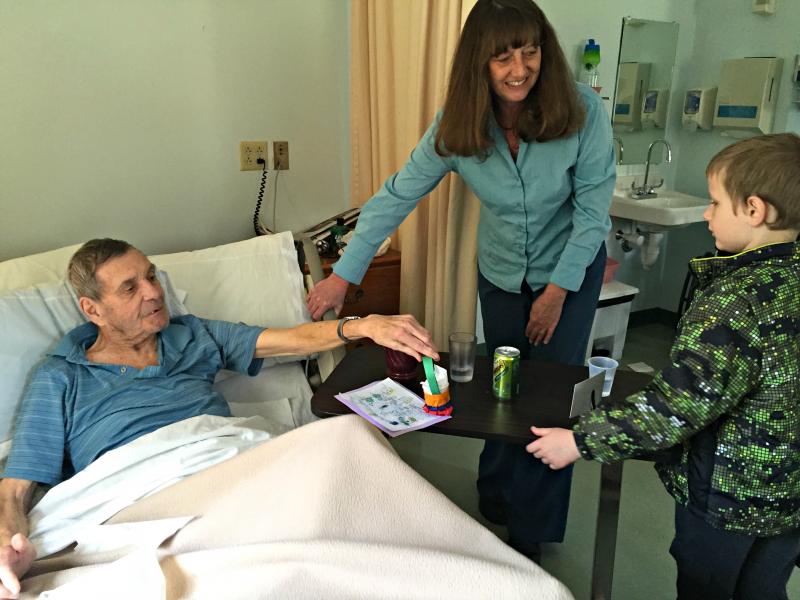 Aiden Wolfe gives his basket to resident John Laird right after Jeri Phinney introduces them. KATRINA CLARK/Boothbay Register