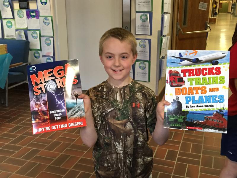 Nicholas Giles holds up his finds at the book fair. KATRINA CLARK/Boothbay Register