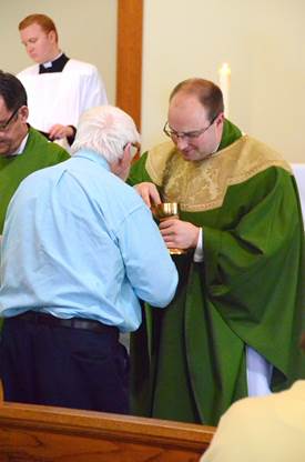 Father Steven Cartwright serves Communion to Henry Rowe. Courtesy of Lois Czerniak, Roman Catholic Diocese of Portland