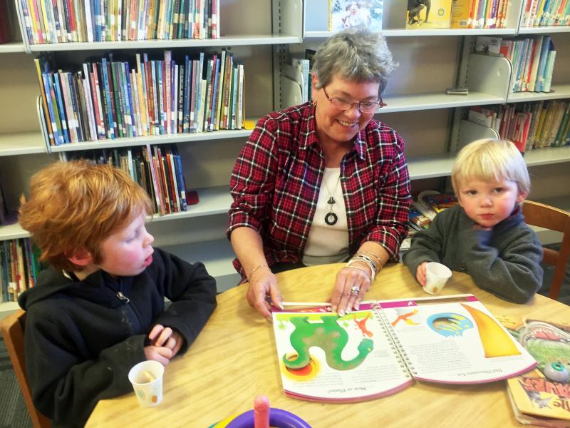 Mary Pinkham, with Camen, left, and Caleb Kearns, doing what she has loved doing for 29 years – reading to children at the Boothbay Harbor Memorial Library. SUZI THAYER/Boothbay Register