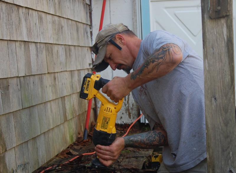 Volunteer Kevin Rogers cuts away at a rotten deck. ART MAYERS/Boothbay Register