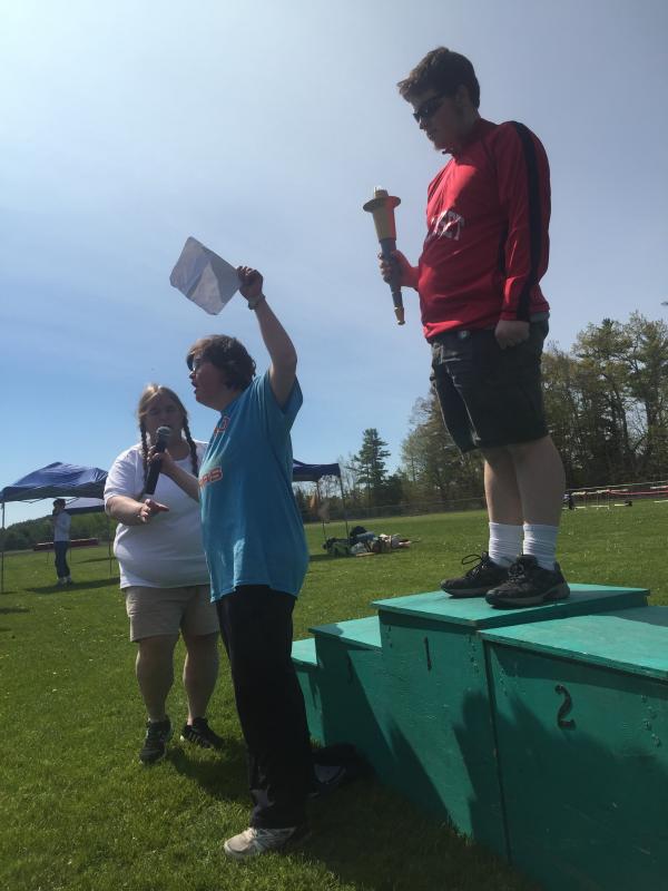 Adult Special Olympics competitor and Wiscasset resident Anna McDougal gives the athlete oath at opening ceremonies at the Wiscasset Middle High School track May 20. WMHS senior Erik Hutchison holds the torch. Near McDougal is Boothbay schools special education teacher, and Special Olympics’ area manager for Lincoln and Sagadahoc counties, Toby LeConte. SUSAN JOHNS/Wiscasset Newspaper