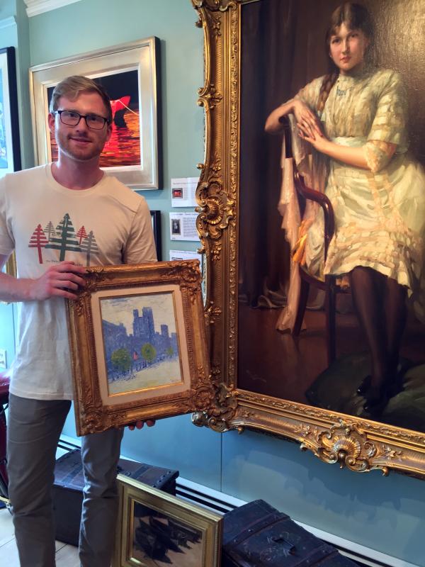 Ryan Hinton holds a painting, “New York City,” by Frederick Childe Hassam. The Fernand Toussaint.painting, “La Jeune Femme, is to his right. SUZI THAYER/Boothbay Register