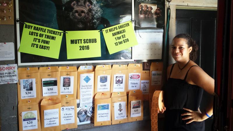 Reanna Heino of Two Salty Dogs Outfitters stands in front of the wall of fabulous prizes that will be won with raffle tickets at the 4th annual Mutt Scrub on July 30. Courtesy of Susan Reynolds