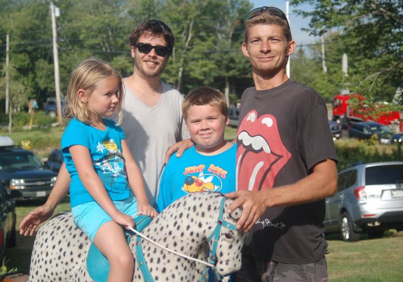 Makayla Abbe enjoys a hobbyhorse her family won at the auction. Pictured with her are Brian Abbe, Ben Abbe and Trevor Swope. ART MAYERS/Boothbay Register
