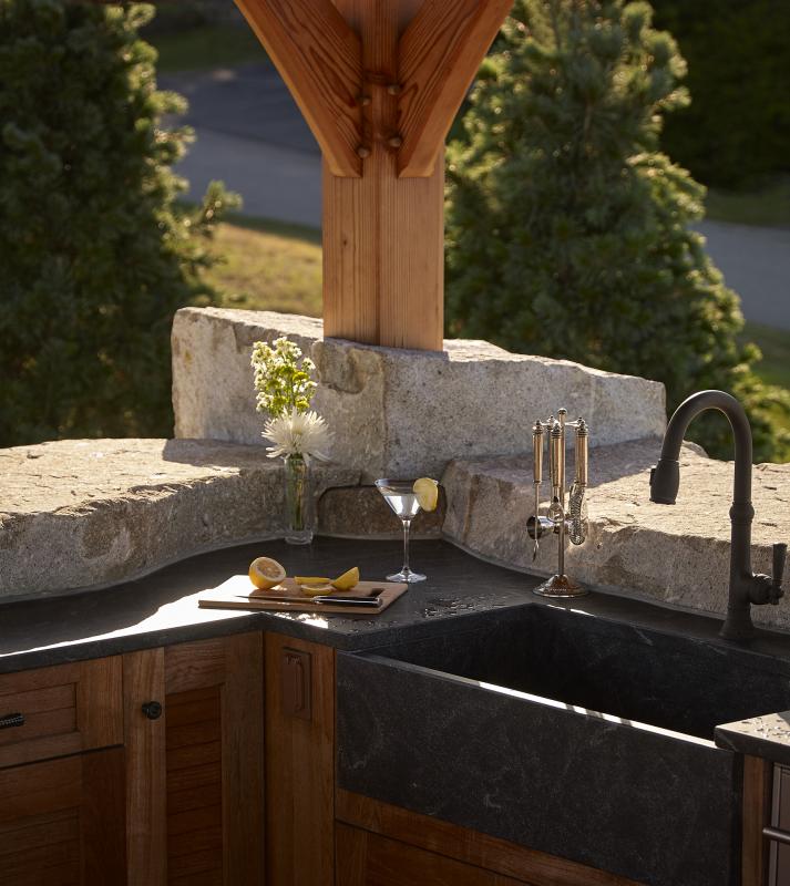 An outdoor cabana kitchen has fir columns rising out of a rough cut stone bar, carved to follow the honed surface of the stone counter top; the cabana’s textures and materials reinforce its close connection to nature. Learn more about the art and architecture of working with stone on Tuesday, Aug. 16 at the Boothbay Railway Village. Photo courtesy Knickerbocker Group.