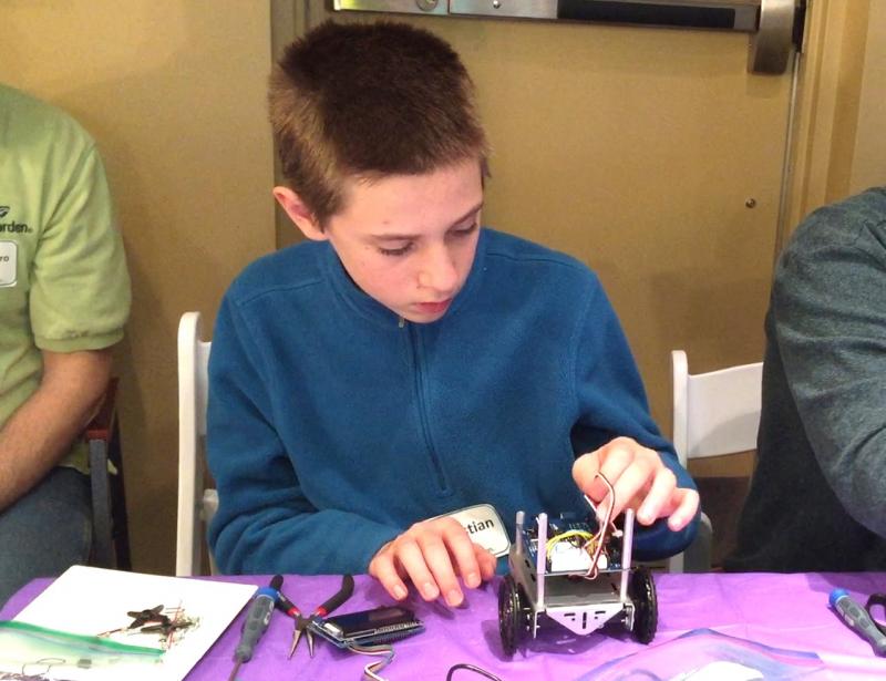 Christian Longobardi of Westport Island plugs motors into the microcontroller of a self-driving robot during Gizmo Garden at Skidompha Library last February. Courtesy photo
