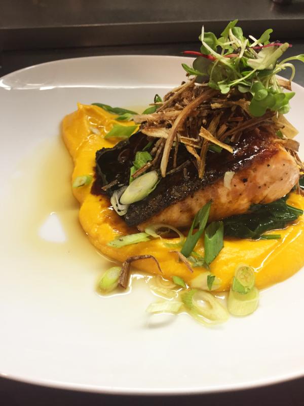 Chef Kelly Farrin’s cast iron roasted skin-on Scottish salmon with sweet potato puree, sauteed spinach, tamari glaze, leek hay strings, fresh scallion and toasted sesame oil, at The Carriage House restaurant in East Boothbay. Courtesy of Kelly Farrin