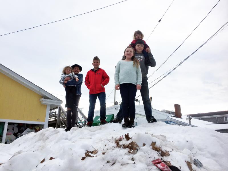 Violet Baldwin, left, Jackson Lorrain, Wyatt Lorrain, Suzie Edwards, Charles Chappelle and Emily Conley gather on a big pile of snow on Pier One outside McSeagull’s on Feb. 19. SUZI THAYER/Boothbay Register