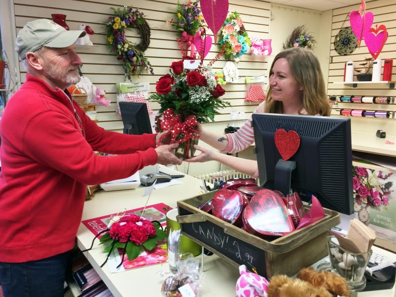 Tim Utley gets a floral arrangement from Boothbay Region Greenhouses employee Breeze Kidder. SUZI THAYER/Boothbay Register