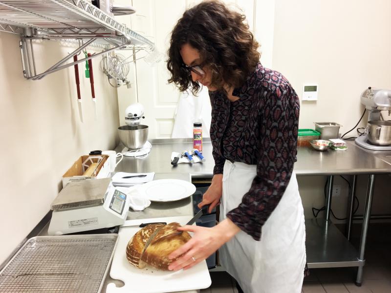 Alex Tallen cuts into a warm loaf of her signature French country boule in her kitchen at the Boothbay Harbor Country Club. SUZI THAYER/Boothbay Register