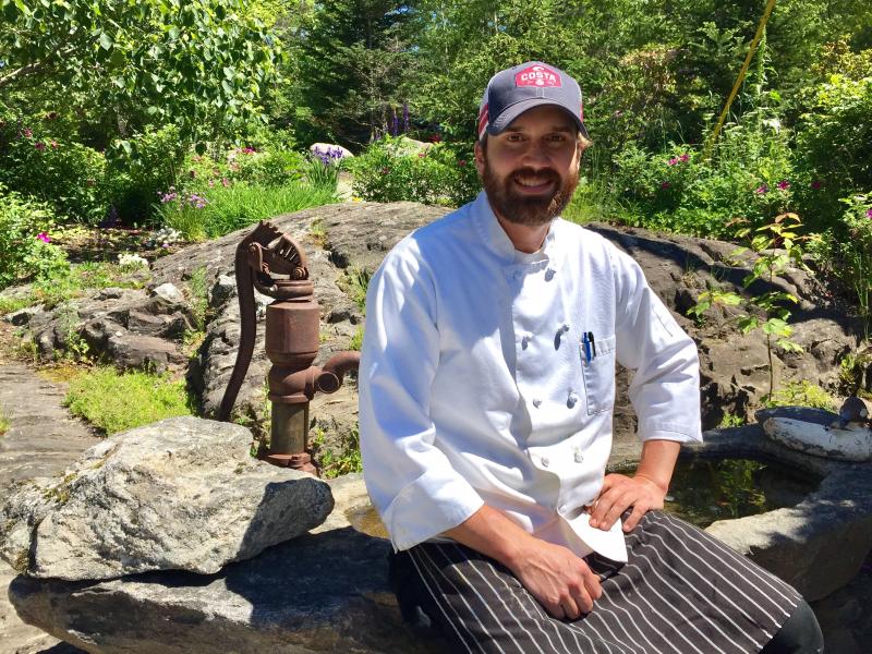 Chef Kelly Patrick Farrin outside his Carriage House Restaurant in East Boothbay. He’s sitting on a stone birdbath made by his father, Pat Farrin. SUZI THAYER/Boothbay Register