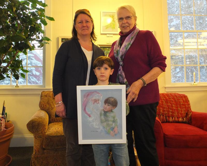 Artist Sue Heil Kibbe, right, with Heather Sinclair and her son Myles Whitfield, gifts the family with a portrait of the boy with Santa during Harbor Lights 2015. LISA KRISTOFF/Boothbay Register Boothbay Register