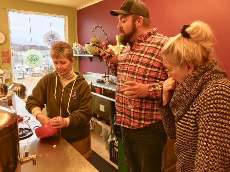Kim Martin rubs garlic over the inside of the fondue pot while Michael Maxim and Andy Bielli sip wine and watch, in the kitchen at Eventide. SUZI THAYER/Boothbay Register