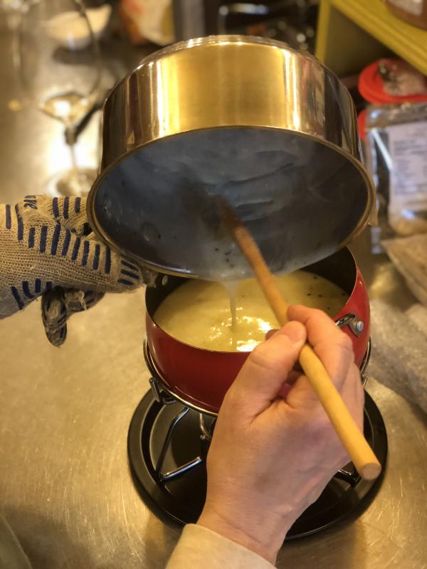 Kim Martin pours the pan of cheese fondue into the pot. SUZI THAYER/Boothbay Register