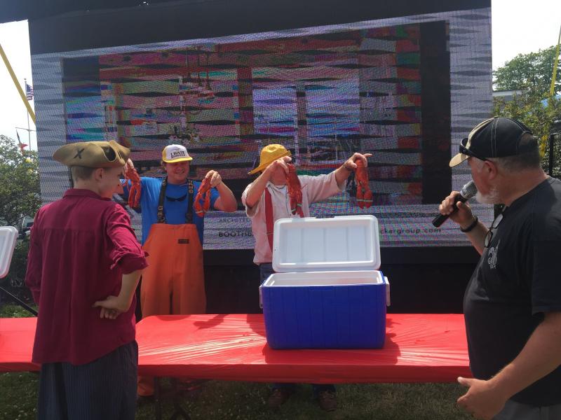 Chris Gleason, back, left and Cap’n Rusty Court show off the mighty fine Maine lobsters to entice contestants. LISA KRISTOFF/Boothbay Register