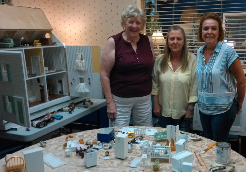 Boothbay resident and project manager Penny Donovan meets with Diane Foley, a Southport summer resident who donated items to the dollhouse project. Stacy Laird, right, donated the house and furniture to the Community Center. JANE CARPENTER/Boothbay Register