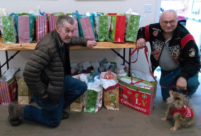 Reid Hodgdon, left, and Daren Graves, assisted by Cinnamon, with gift bags for veterans at the Boothbay Harbor Rotary clubhouse. JANE CARPENTER/Boothbay Register