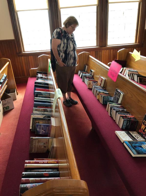 A customer looks over the selection of mysteries and thrillers. CRAIG LANCASTER/Boothbay Register Southport, Southport Country Fair, Southport Town Hall, Southport United Methodist Church