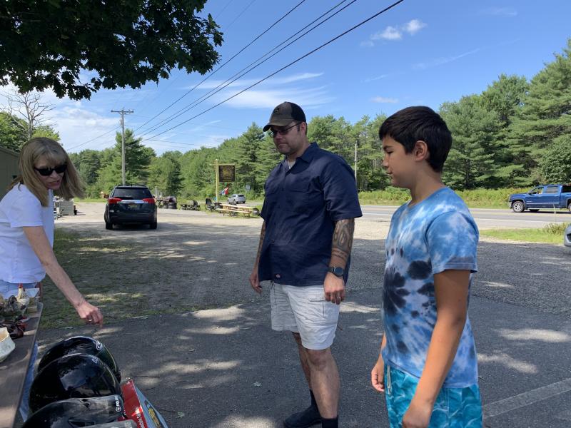 Boothbay Harbor’s Kelley Coady talks helmets outside Miss Wiscasset Diner Aug. 23 with shoppers and past customers Ryan Daniels and son Ismael Martinez, 12, of Westport Island. SUSAN JOHNS/Wiscasset Newspaper