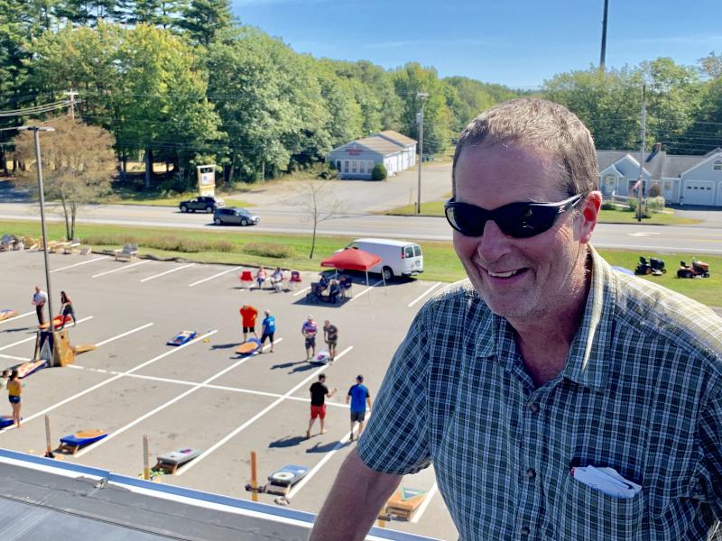 Roof with a view: Ames True Value co-owner Wayne Averill pauses for a photo as entrants warm up below; beyond the lot, Route 1. SUSAN JOHNS/Wiscasset Newspaper