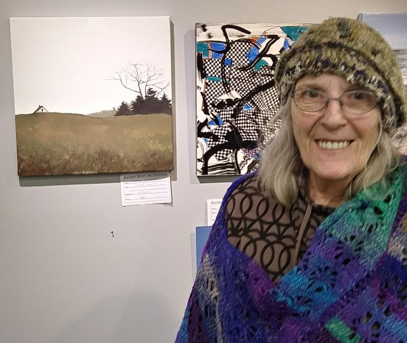BRAF gallery manager June Rose stands next to “Pine Hill” by Nathan Campbell. JANE CARPENTER/Boothbay Register