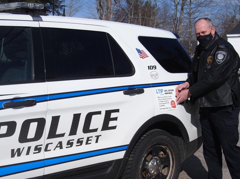 Sgt Hatch of Wiscasset Police Department places a new LTIP decal on his cruiser. Courtesy photo