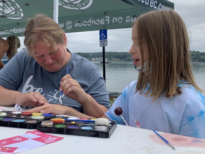 Kristy Lincoln paints the hand of Clover Apezynski, 9, at Schoonerfest Aug. 21. SUSAN JOHNS/Wiscasset Newspaper