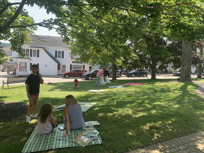 Picnic mats with books are laid out before the event begins. Jessica Doucette and her daughter Emma, 9, sit on a mat. LILLY CURTIS/Boothbay Register