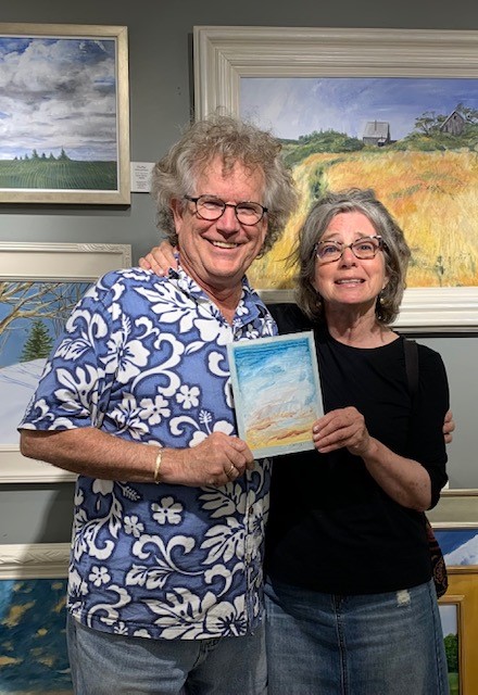 John M.T. Seitzer with Susan Angle with her new artwork. John and Lynne Seitzer have been taking photos with everyone buying their art for 22 years. Courtesy of Joy to the Wind gallery