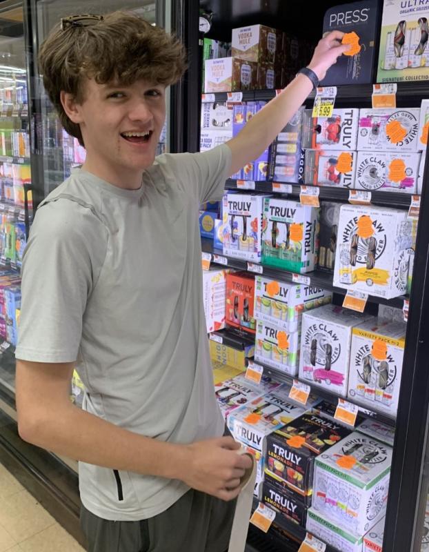Colby Allen was one of the Student Health Advisory Board members who volunteered to place labels on alcohol sold in local stores May 11 to warn adults about laws covering underage drinking. BILL PEARSON/Boothbay Register