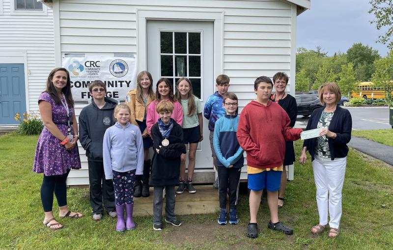 Southport students in grades 3-6, as well as their teacher Mrs. Browne and teaching principal Ms. Lisa Clarke, are shown making the presentation to Tracey Hyson, deputy treasurer of the town of Boothbay. Although the town does not oversee the Community Fridge, it is located beside the Boothbay Town Office where anyone in need may access it at any time. Courtesy photo