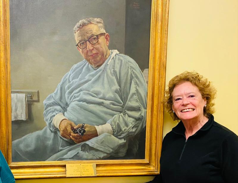 Auxiliary member Sarah Giles beside the portrait of her father-in-law, Dr. Phillip Gregory. Courtesy photo